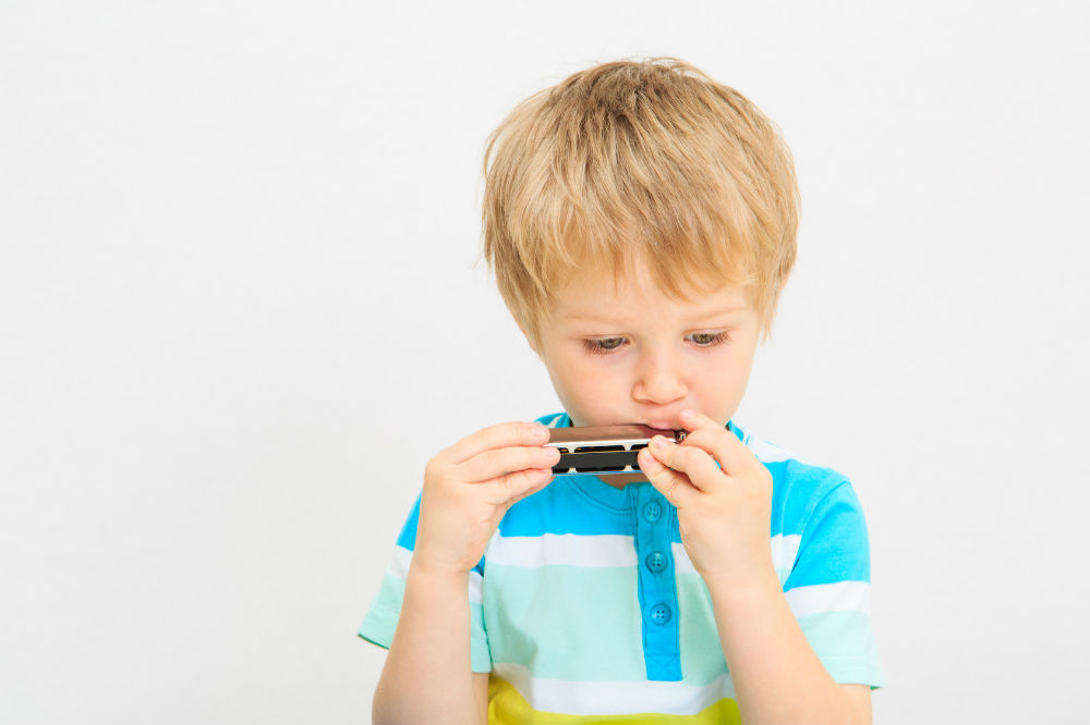little boy playing the harmonica